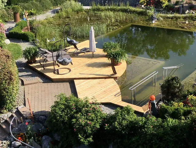 Gepflegte Gartenanlage mit Naturteich und Sitzbereichen auf einem Wellnesshof im Allgäu, umgeben von Grün und ruhiger Urlaubsatmosphäre.