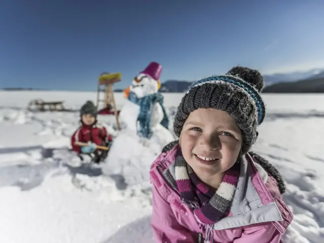 zwei Kinder bauen einen Schneemann